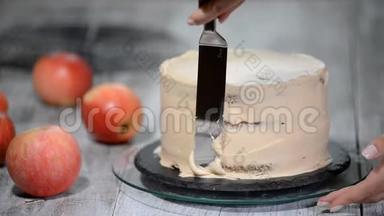 厨师用奶油装饰一个美味的蛋糕。 制作焦糖苹果蛋糕
