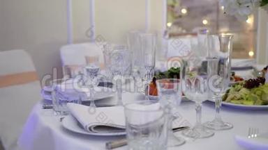 眼镜，盘子，餐具和餐巾.. 为聚会装饰了鲜花的桌子。 婚宴，生日