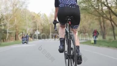 女骑自行车的人踩着自行车。 后面跟着射击。 自行车上的腿部肌肉。 自行车的概念。