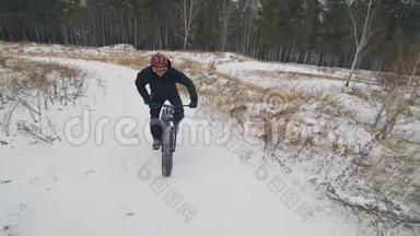 专业的极限运动员骑自行车在户外骑胖自行车。 骑自行车在冬天的雪林里。 男人是审判