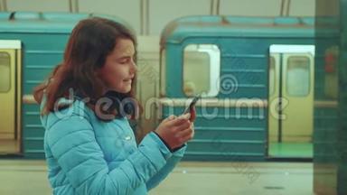 少女在地下<strong>地铁</strong>里乘<strong>地铁</strong>等待火车的到来，手持智能手机。 小女孩