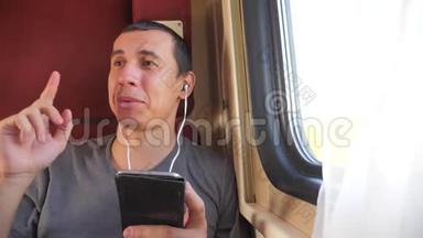 男子听着火车车厢车厢车厢车厢上的音乐旅行。 生活方式慢动作视频。 一个男人