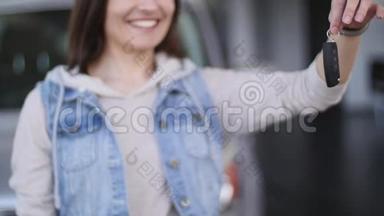年轻女子拿着新车的钥匙对着镜头微笑