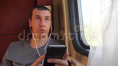 男子听着火车车厢车厢车厢车厢上的音乐旅行。 慢动作视频。 有智能手机的男人