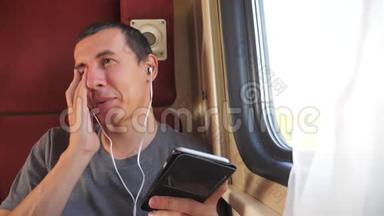 男子听着火车<strong>车厢车厢车厢</strong>里的音乐生活方式旅行。 慢动作视频。 一个男人