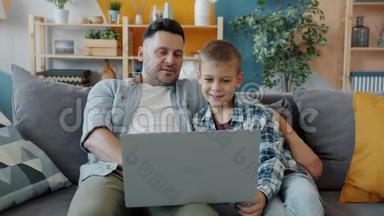 成年男子和小孩用手提电脑打字，看屏幕，在家大笑
