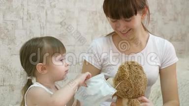 小女孩检疫，在玩具熊上戴上医疗面具。 预防冠状病毒和流感。 婴儿游戏
