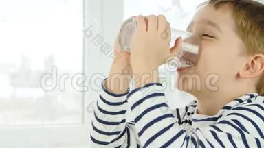 一个小男孩从杯子里喝牛奶，体验快乐、快乐、笑声的情绪。 健康，自然，婴儿食品