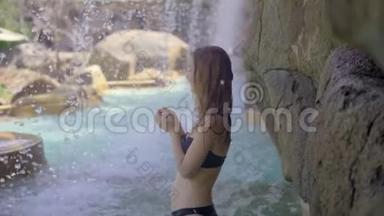 一位年轻女子在热带度假胜地，有<strong>温泉</strong>、瀑布和<strong>游</strong>泳池，有热水。 慢动作