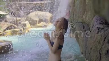 一位年轻女子在热带度假胜地，有<strong>温泉</strong>、瀑布和<strong>游</strong>泳池，有热水。 慢动作
