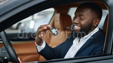 特写商人在新车里摇动钥匙。 在车里微笑的非洲男人