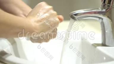 美丽女人的双手用泡沫洗手池洗手，洗皮肤，水从手中流过