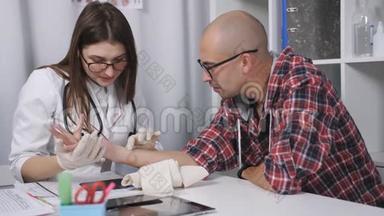 医生检查了病人手腕受损的x光片。 医生检查病人