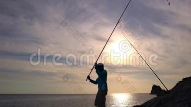 泰国普吉岛海岸岩石上的渔夫剪影，美丽的日落或日出时间