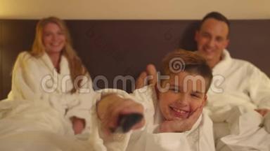 在酒店房间里的家人，父母坐在床上，儿子在电视上切换香奈儿，慢动作