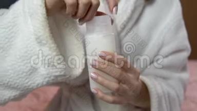 女人关上洗发水的盖子。 穿着浴袍的女人拿着一罐旅行洗发水。 特写