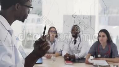 年轻的多民族实习生在诊所的医学会议上聆听非洲美国医生的讲座。 在讲座期间
