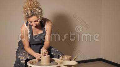 在陶工`轮子上工作的女人。 双手用泥壶雕刻一个杯子
