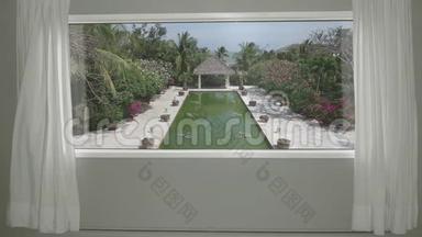 从酒店房间可以看到宁静的热带度假胜地，有花园和游泳池。 背景板，彩色关键视频背景
