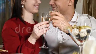情侣们在一次约会中在一家餐馆里碰杯。 特写镜头。 年轻人和女人在餐馆里喝浪漫晚餐