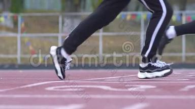 三个年轻人开始在体育场跑步机上从低起点开始跑步，跑步者采用低起点健康的生活方式