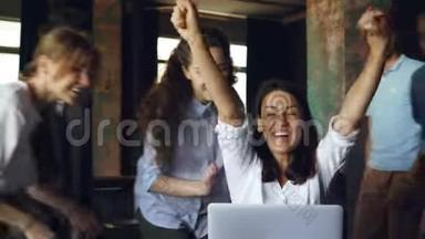 漂亮的黑发女人正在用电脑工作，笑着，她的团队要来祝贺她取得了好<strong>成绩</strong>，人们