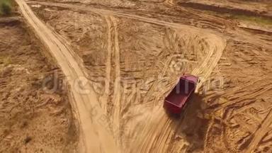 空的大型红色卡车在沙漠或沙丘中的沙子轨道上移动的鸟瞰图。 美丽的景色
