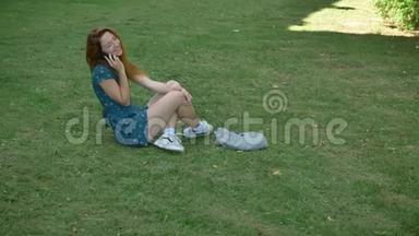 美丽的姜<strong>女</strong>在电话里谈笑风生，坐在草地上，快乐开朗的<strong>女孩子</strong>在说话
