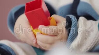 一岁的小男孩正在玩彩色塑料砖乐高。 快乐的小宝宝玩五颜六色的乐高