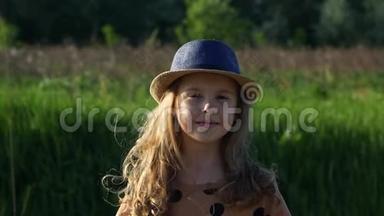 一个戴着夏帽的快乐孩子在大风天气里看着镜头