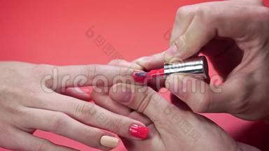 摩尼教`<strong>客户</strong>的指甲用米色涂指甲油，涂在红色<strong>背景</strong>、化妆品和指甲上，并将指甲贴紧