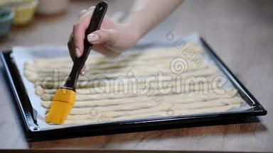 厨房里的女人用橄榄油刷格里西尼。 烹饪意大利格里西尼。