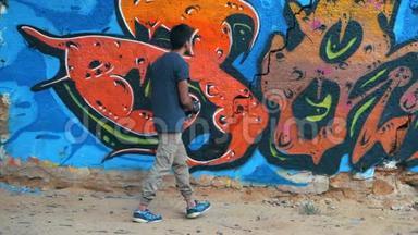 创意艺术-少年画彩色抽象装饰涂鸦在街墙与气溶胶喷雾。 慢动作