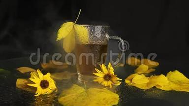 在秋天的景色中，一个透明的玻璃杯被热<strong>茶树</strong>的雨打湿了