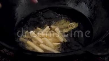一个女人把土豆扔进一锅<strong>沸腾</strong>的油里。 切片土豆<strong>沸腾</strong>在油特写。 慢慢地。