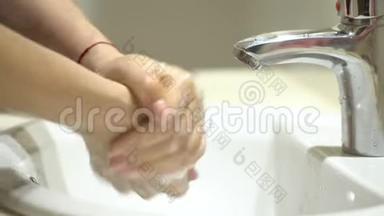 美丽女人的双手用泡沫洗手池洗手，洗皮肤，水从手中流过