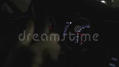 一个汽车仪表盘的特写，而男子开车到城市街道在夜间。