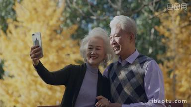 幸福的<strong>老年</strong>夫妇坐在户外用手机拍照