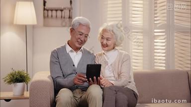 老年夫妇坐在<strong>沙发</strong>上看平板电脑