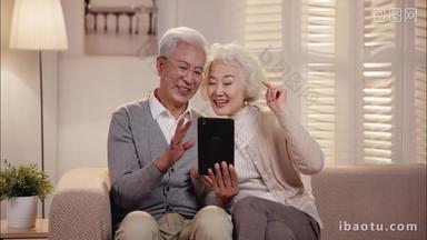 老年夫妇坐在沙发上看平板电脑