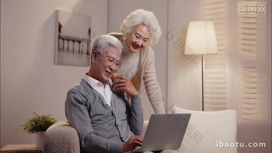 老年夫妇坐在<strong>沙发</strong>上使用笔记本电脑