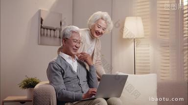 老年夫妇坐在<strong>沙发</strong>上使用笔记本电脑
