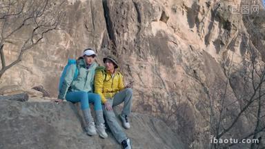 青年登山者伴侣坐在岩石上看风景