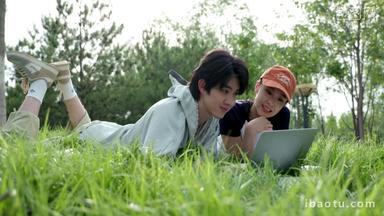 <strong>青年</strong>情侣趴在草地上用电脑