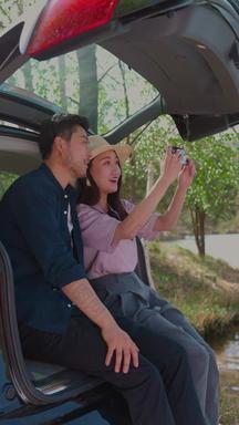 自驾游的青年夫妻用手机拍照