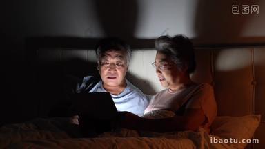 老年夫妇<strong>坐在床上</strong>使用平板电脑