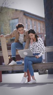 快乐商务情侣在户外使用笔记本电脑