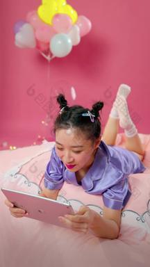 年轻女孩趴在床上看平板电脑