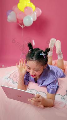 年轻女孩趴在床上看平板电脑