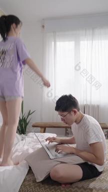 年轻情侣坐在床上用电脑